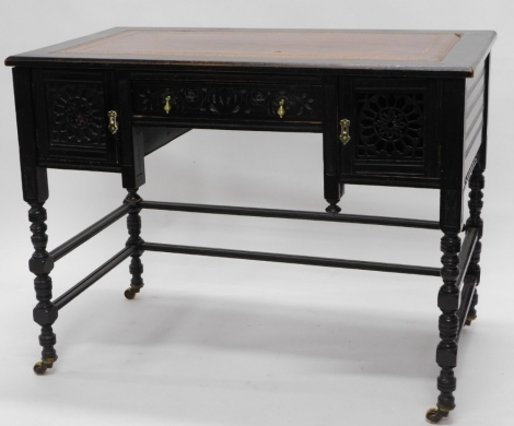 A 19thC ebonised Aesthetic movement writing table, the rectangular top with a brown and gilt tooled leather inset, above a freeze drawer flanked by two pierced cupboard doors, on part turned supports with stretcher, in the manner of Gillows, 77cm high, 10