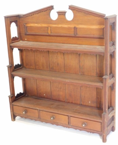 A late 19th/early 20thC pine waterfall bookcase, with an arched crest, shaped sides and reeded supports, the two shelves above three drawers each with turned wood handles centred by a mother of pearl, 104cm high, 92cm wide.