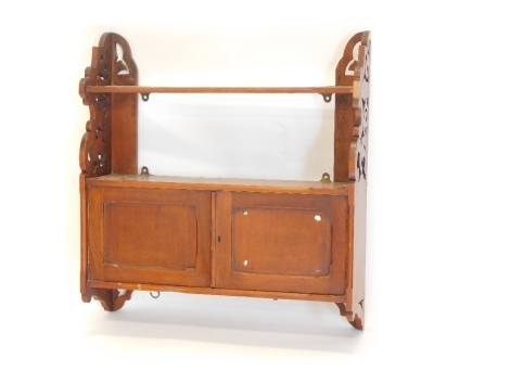 A mahogany wall shelf, with shaped end supports and two panelled doors, 62cm wide.