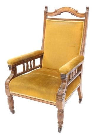 A late Victorian oak armchair, the back, arms and seats overstuffed in gold coloured material, on turned front legs terminating in castors, 110cm high.