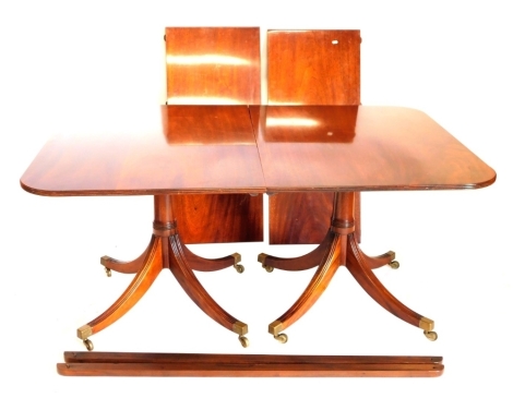 A Regency style mahogany extending dining two pillar dining table, the rectangular top with rounded corners and a reeded edge, on turned columns and slayed legs, 73cm high, 210cm wide, 106cm deep.