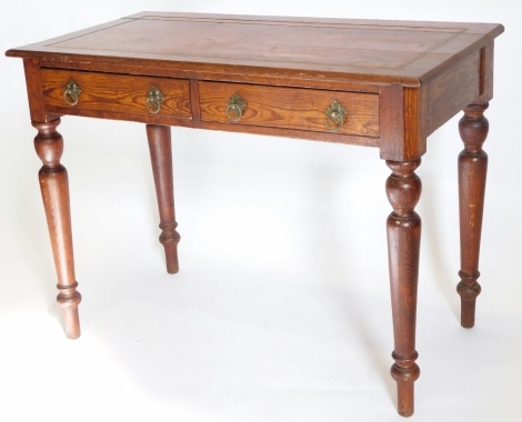 A Victorian pitch pine writing table, the rectangular top with a shaped edge above two frieze drawers, each with Gothic style brass handles, on turned tapering legs, 99cm wide.