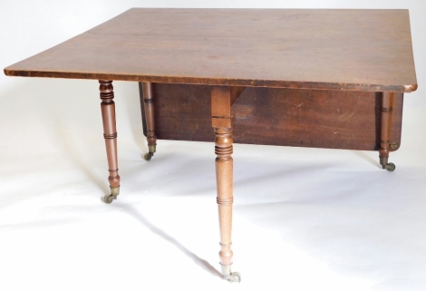 A George III mahogany drop leaf table, the rectangular top on turned tapering legs with brass castors, 73cm high, 122cm wide, 174cm deep.