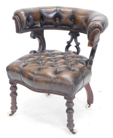 A Victorian oak library chair, upholstered in brown button leather, with scroll shaped supports, on turned legs with castors.