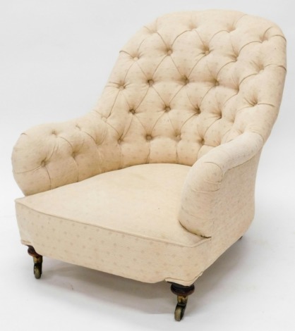 A Victorian mahogany armchair, upholstered in a buttoned beige fabric, on turned legs with brass castors.