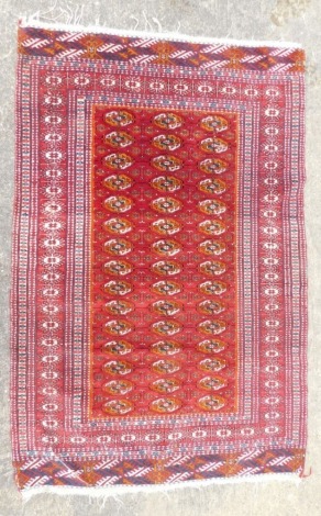 An Afghan rug, with a design of medallions on a red ground, with multiple borders.