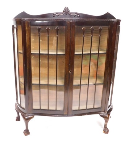 A 1920s mahogany display cabinet, with shaped crest, a carved frieze above two glazed doors enclosing fabric lined shelves, on cabriole legs with ball and claw feet, 119cm wide.