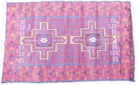 A Belouch rug, with a star design surrounded by geometric devices in red on a navy blue ground with multiple borders, 124cm x 79cm.