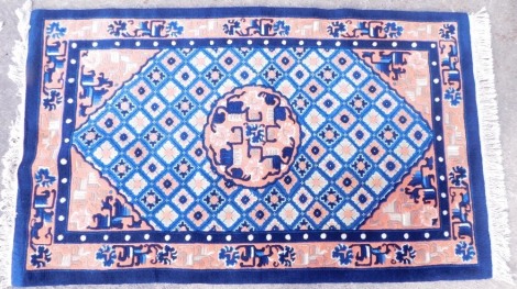 A Chinese rug, with a design of geometric and other devices, in navy blue and coral and cream, on a blue ground with one wide border, 156cm x 93cm.