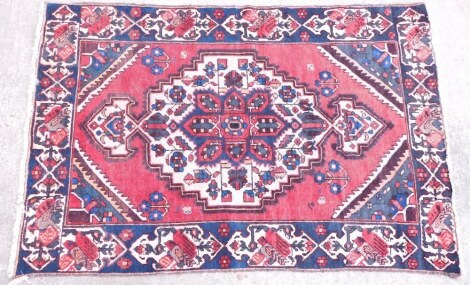 A Persian rug, with a central pole medallion, on a red ground with one wide border, 190cm x 128cm.