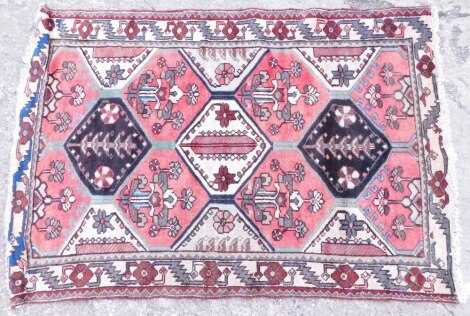 A Persian rug, with a design of flowers within medallions in brown and pink, one wide, one narrow border, 180cm x 124cm.