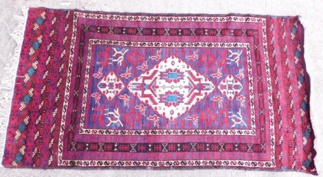 A Persian rug, with a geometric design of medallions on a purple ground with multiple borders.