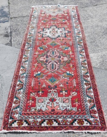 A vintage washed red ground Persian runner, in traditional medallion pattern, 310cm x 115cm.