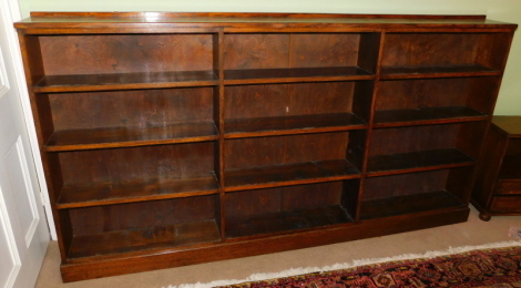 An early 20thC oak free standing bookcase, set with a number of shelves, 125cm high, 228cm wide, 24cm deep.