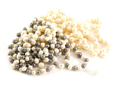 A group of pearls, comprising a two colour natural pearl necklace, with knotted strand and grey and cream finish beads, 148cm long, together with another cream lustre finish example, 110cm long with single strand knot, together with a group of loose beads