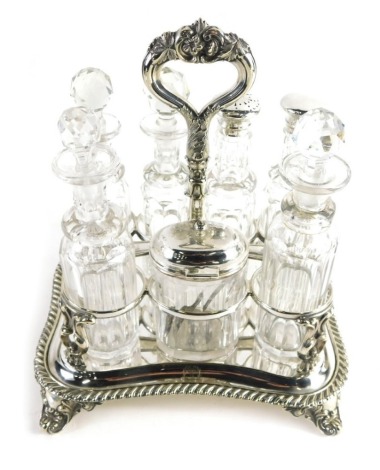 An Edwardian silver plated bottle cruet set, Savory family crest, containing various silver mounted cut glass bottles, on a serpentine stand terminating in scroll feet, centred by a floral handle, 28cm high.