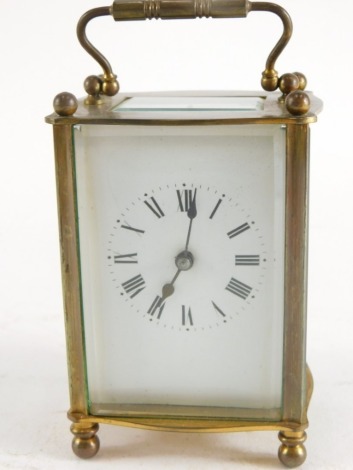 A French brass carriage clock, in shaped case with enamelled dial and swing handle, 15cm high.