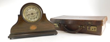 An Edwardian mahogany boxwood strung mantel timepiece, in Napoleon hat shaped case, with silvered dial, on bun feet, 28cm wide, and a small leather case.