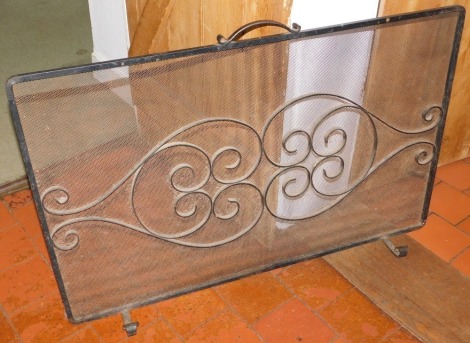 A wrought iron spark guard, 66cm high, 106cm wide.