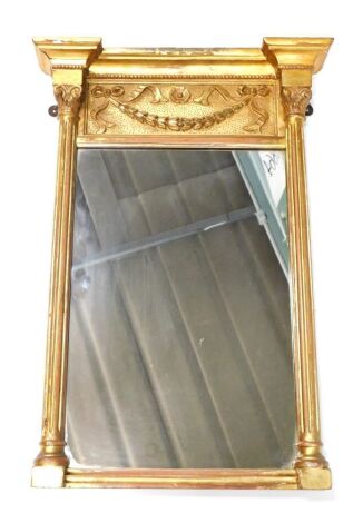 An early 20thC gilt wood wall mirror, of inverted breakfront form, raised with garlands and floral roundels, the plain glass flanked by composite columns, 55cm x 38cm.