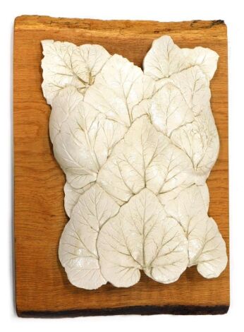 A 20thC floral Studio pottery wall hanging sculpture, formed as veined leaves on a wooden backing, in cream, unsigned.