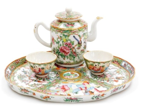 A 19thC Chinese Canton decorated cabaret part tea set, the shaped tray decorated with figures within scroll borders in pink, blue, and green, picked out in gilt, a teapot and two bowls, the tray 27cm diameter.