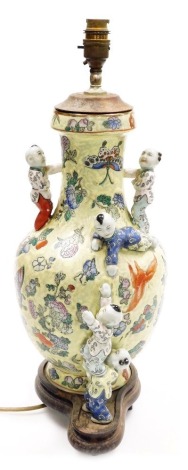 A Chinese porcelain vase, decorated with butterflies and flowers, against a mottled green ground with applied figures of children, on a hardwood base, converted into a table lamp, 51cm high overall.