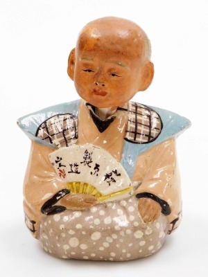 An early 20thC Japanese pottery nodding figure, modelled as a seated sage holding a fan, bears script, 15cm high, together with a Chinese brass and enamel napkin ring. (2) - 2