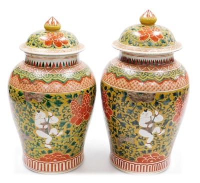 A pair of Chinese porcelain baluster jar and covers, decorated with boys clambering among scrolling peonies, six character Kangxi mark to underside, 41cm high.