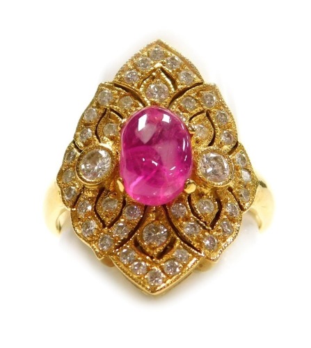 A cabachon ruby and diamond lozenge shaped dress ring, a central ruby of 8.1mm x 5.4mm, surrounded by tiny diamonds in a pierced precious yellow metal mount, forty four approx in total, size L, 5.6g all in, ruby is heavily included.