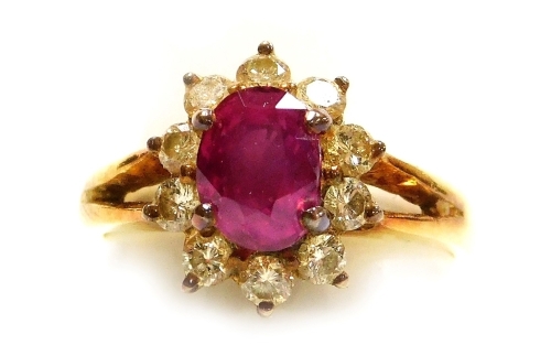 A ruby and diamond set cluster dress ring, the central oval faceted ruby of 6.1mm x 5.2mm surrounded by ten tiny diamonds, set in precious yellow metal, size I, 4g all in.