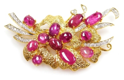 A cabachon ruby and diamond set floral spray brooch, twelve cabachon rubies between 8.2mm and 4.4mm in length, set in a spray formation with tin diamond set ribbon tails, the whole in precious yellow metal, 6cm x 4cm total, pin and safety loop back, 17.15