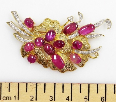 A cabachon ruby and diamond set floral spray brooch, twelve cabachon rubies between 8.2mm and 4.4mm in length, set in a spray formation with tin diamond set ribbon tails, the whole in precious yellow metal, 6cm x 4cm total, pin and safety loop back, 17.15 - 2