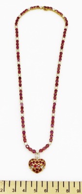 A heart shaped pendant on stone set chain, the pierced pendant set with oval faceted rubies, tiny diamond set suspension loop to ruby and diamond set necklace, each ruby average 1.8mm, each diamond average 2mm, all set in precious yellow metal, 38cm long - 2