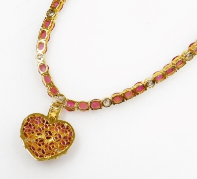 A heart shaped pendant on stone set chain, the pierced pendant set with oval faceted rubies, tiny diamond set suspension loop to ruby and diamond set necklace, each ruby average 1.8mm, each diamond average 2mm, all set in precious yellow metal, 38cm long - 3