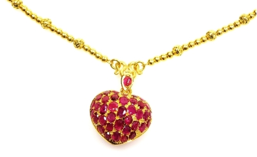 A heart shaped ruby set pendant on heavy bead necklace, the pierced heart locket set with variously shaped stones to ruby set suspension loop on a beaded necklace, the whole in precious yellow metal, 62cm long, 41g all in.