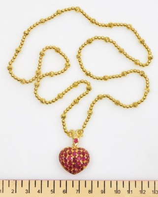 A heart shaped ruby set pendant on heavy bead necklace, the pierced heart locket set with variously shaped stones to ruby set suspension loop on a beaded necklace, the whole in precious yellow metal, 62cm long, 41g all in. - 2