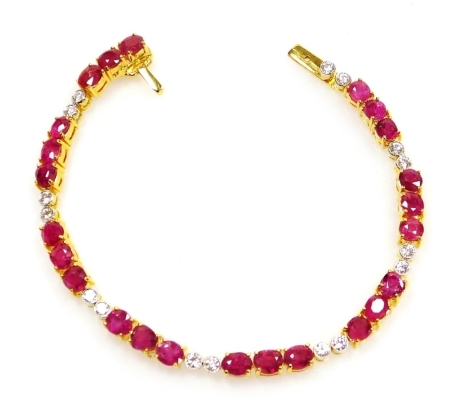 A ruby and diamond set tennis style bracelet, twenty four rubies of 4mm x 3.5mm average, in groups of three interset with eight pairs of diamonds, 2mm x 2.5mm average, all in precious yellow metal, 15.1g all in, 17cm long.