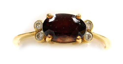 A stone set dress ring, a central oval brown/orange faceted stone, 7mm x 5mm, with a pair of tiny diamonds to each side, in yellow precious metal, 2.3g all in, size L.