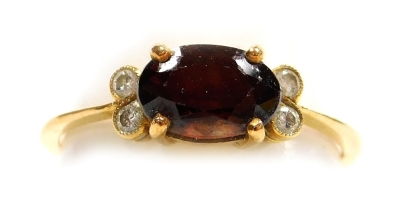 A stone set dress ring, a central oval brown/orange faceted stone, 7mm x 5mm, with a pair of tiny diamonds to each side, in yellow precious metal, 2.3g all in, size L.