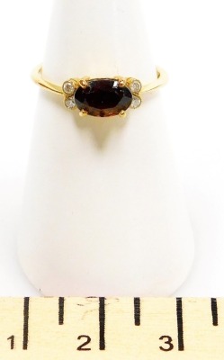 A stone set dress ring, a central oval brown/orange faceted stone, 7mm x 5mm, with a pair of tiny diamonds to each side, in yellow precious metal, 2.3g all in, size L. - 2