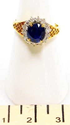 A sapphire and diamond cluster dress ring, the central stone of 6.6mm diameter surrounded by fourteen tiny diamonds, all in precious yellow metal, size N, 5.6g all in. - 2