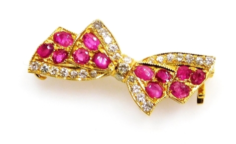 A ruby and diamond set bow brooch, set with twelve rubies of 2mm average with accents of tiny diamonds, 3cm x 1.5cm, all in precious yellow metal, 4.7g all in.