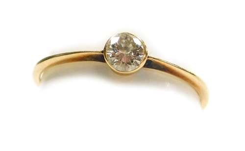 A solitaire diamond ring, the stone of 2.5mm diameter, in rub over setting to yellow metal shank, size G½, 0.72g all in.