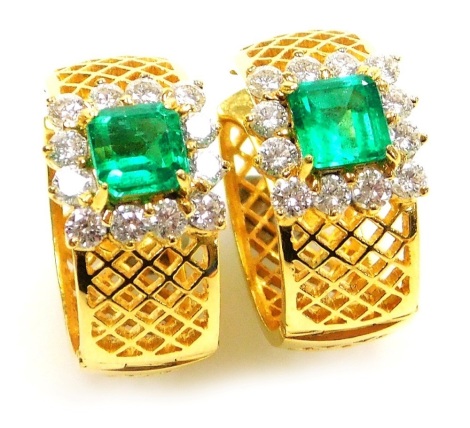 A pair of emerald and diamond set hoop earrings, on hinged post backs, each set with a square cut emerald 5.7mm square, surrounded by twelve diamonds of 1.8mm diameter average, to yellow metal settings, 13.76g all in.