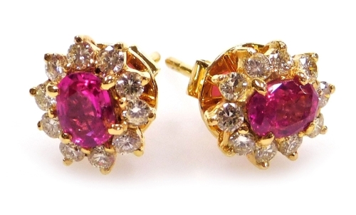 A pair of ruby and diamond cluster earrings, the central facet cut ruby of 6.1mm x 5.2mm surrounded by ten round brilliant cut diamonds of 1.5mm diameter average, post and butterfly backs, set in precious yellow metal, 5.1g all in.