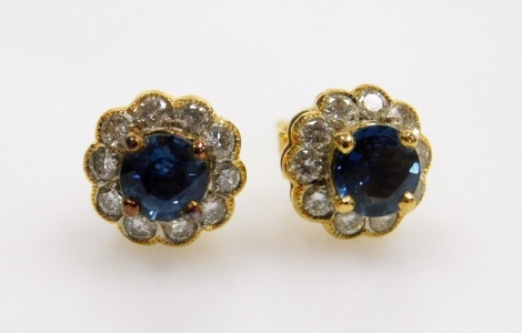 A pair of sapphire and diamond cluster earrings, the central oval faceted sapphire of 5.2mm x 4.5mm approx, surrounded by ten tiny diamonds, post and butterfly backs, 8.2mm x 7.3mm each, set in precious yellow metal, 3.3g all in.