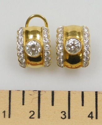 A pair of diamond set clip and post earrings, the central diamonds of 5.5mm diameter each flanked by two rows of seven tiny diamonds, all round brilliant cut, 1.5cm x 1.1cm each, set in precious yellow metal, 8.04g all in. - 2