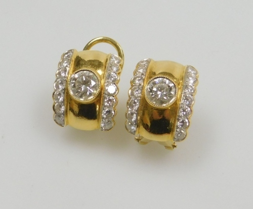 A pair of diamond set clip and post earrings, the central diamonds of 5.5mm diameter each flanked by two rows of seven tiny diamonds, all round brilliant cut, 1.5cm x 1.1cm each, set in precious yellow metal, 8.04g all in.