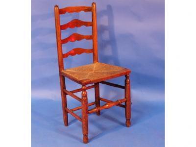 An Arts and Crafts style elm ladder back chair with rush seat